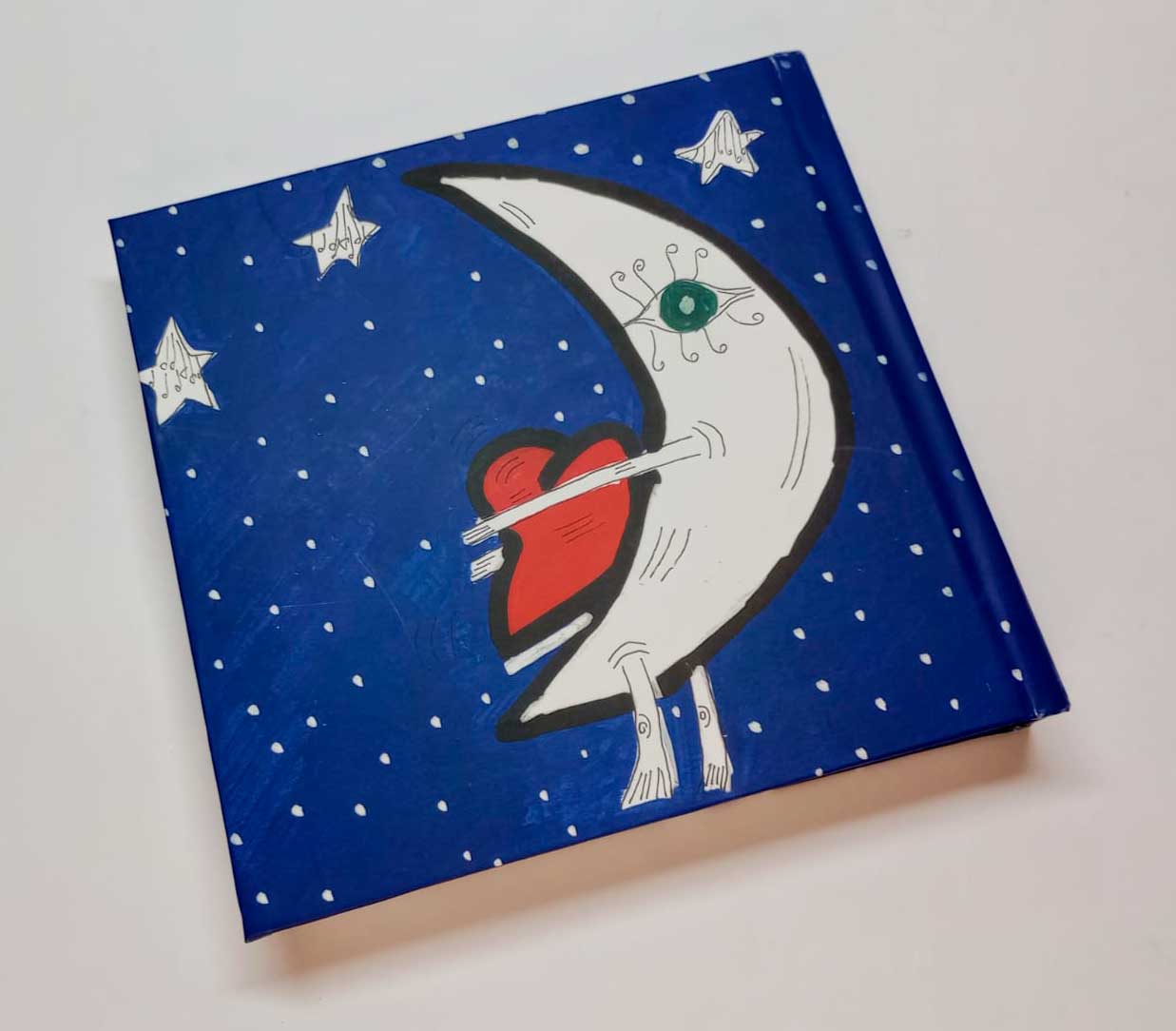 Contratapa del libro Noches de Julio Resek con ilustración de luna abrazando un corazón rojo sobre fondo azul estrellado