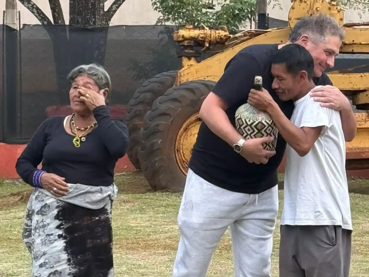 Julio Resek abraza a Domingo Moreira de la comunidad Mbya Guaraní Ivytu Porá sosteniendo la pieza de cestería tradicional que recibe como obsequio, sede de Constructora Resek, Posadas, Misiones, mayo 2026